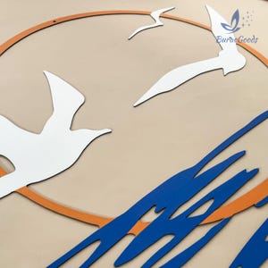 May include: A decorative wall art piece featuring white seagulls, an orange circle, and blue abstract shapes against a beige background. The artwork includes the text "BuracGoods".