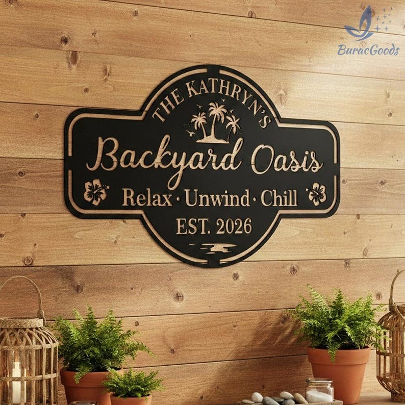 Puede incluir: Letrero de metal negro con el texto "The Kathryn's Backyard Oasis" y las palabras "Relax, Unwind, Chill" y "EST. 2026". El letrero presenta palmeras y detalles florales. Est&aacute; montado en una pared de madera.