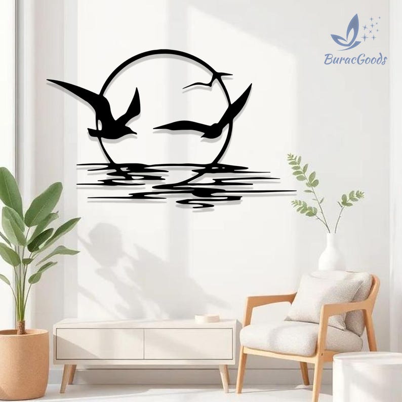 May include: Black metal wall art depicting seagulls in flight against a circular sun, with water reflections below. The artwork features a minimalist design, suitable for home decor. The brand name "BuracGoods" is visible in the upper right corner.