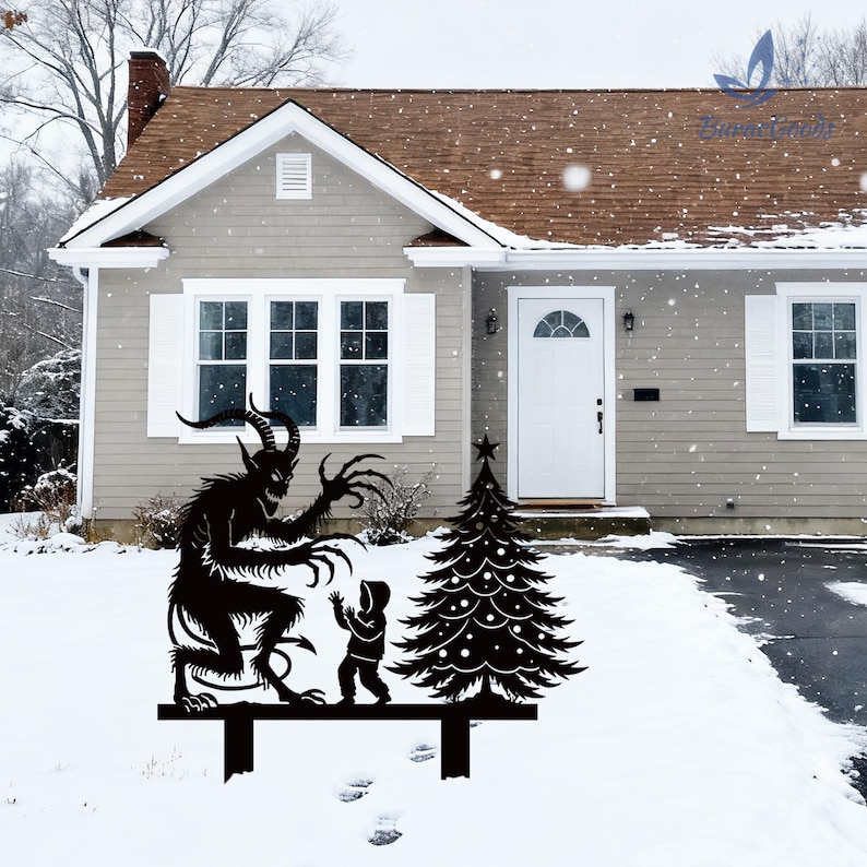 May include: Black metal yard art depicting a Krampus figure menacing a child next to a Christmas tree. The silhouette is mounted on a black bar, set in a snowy yard in front of a house.