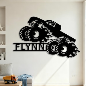 May include: Black metal wall art of a monster truck with flames and the word "FLYNN" in a bold font. The truck has large tires and is angled as if in motion. This decorative piece is suitable for a child's room or a garage.