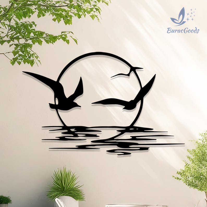 May include: Black metal wall art depicting three seagulls in flight within a circular frame, above stylized water lines. The design includes the text "BuracGoods" in the upper right corner. The artwork is mounted on a light-colored wall.