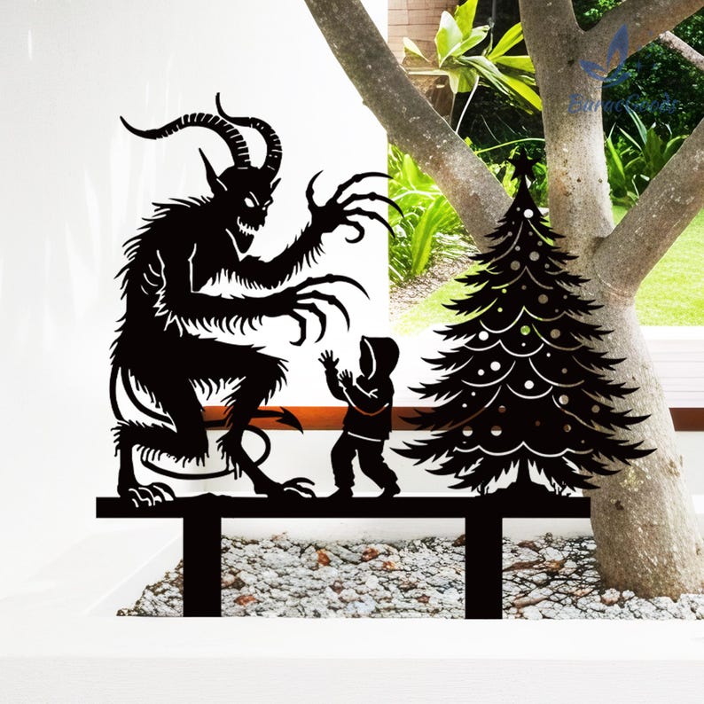 May include: Black metal yard art depicting a Krampus figure menacing a child near a Christmas tree. The silhouette shows the horned beast with long claws and a child in a hooded coat. The Christmas tree has decorative cutouts.