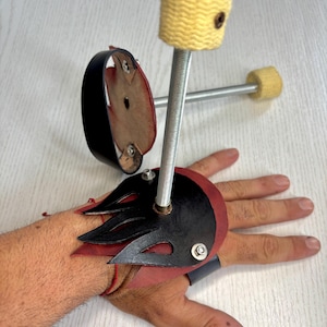 Peut inclure: Un ensemble d'accessoires de danse de feu. Il comprend un bracelet en cuir noir et rouge avec un motif de flamme, deux mèches de feu fixées à des tiges métalliques et une sangle de poignet en cuir noir.