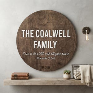May include: A circular dark brown wooden wall sign featuring the white raised text THE COALWELL FAMILY, followed by the script text Trust in the LORD with all your heart. Proverbs 3:5-6 and the black text EST. 2026 centered on the wood grain surface.