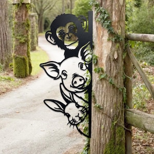 May include: Black metal garden art featuring a monkey, pig, and rabbit peeking around a corner. The whimsical design is cut out, creating a playful silhouette. The art is mounted on a wooden post, adding a touch of rustic charm to outdoor spaces.