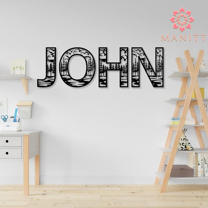 Pode incluir: Arte de parede em metal preto com a palavra "JOHN" com uma cena da natureza recortada em cada letra. As letras apresentam &aacute;rvores, &aacute;gua e p&aacute;ssaros. A arte de parede &eacute; exibida em uma parede branca.