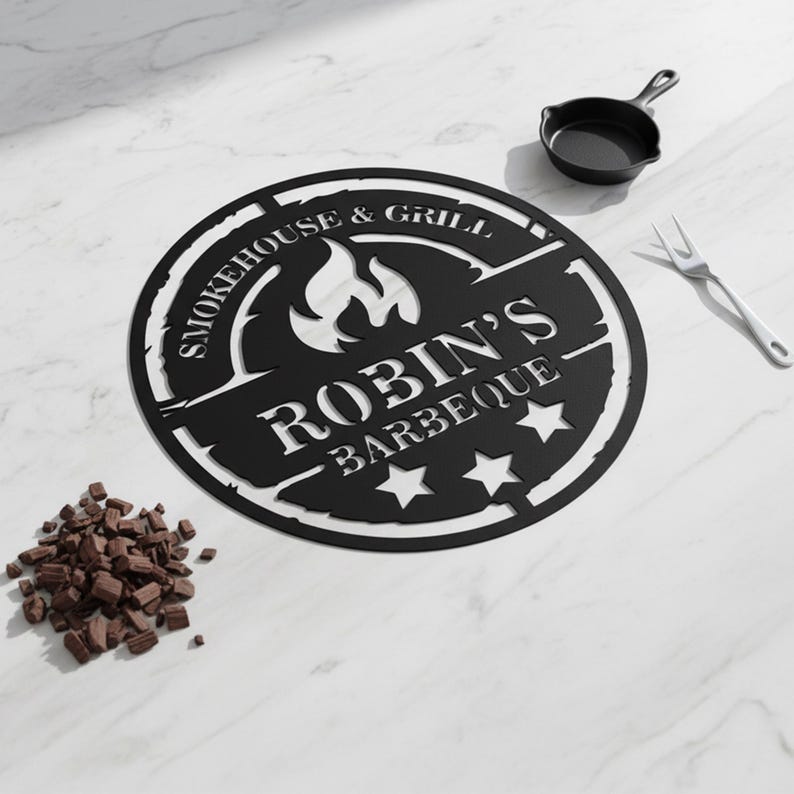 May include: Black metal sign with the text "SMOKEHOUSE & GRILL ROBIN'S BARBEQUE" and three stars. A small cast iron skillet and a fork are next to the sign. A pile of chocolate chips is in the lower left corner.