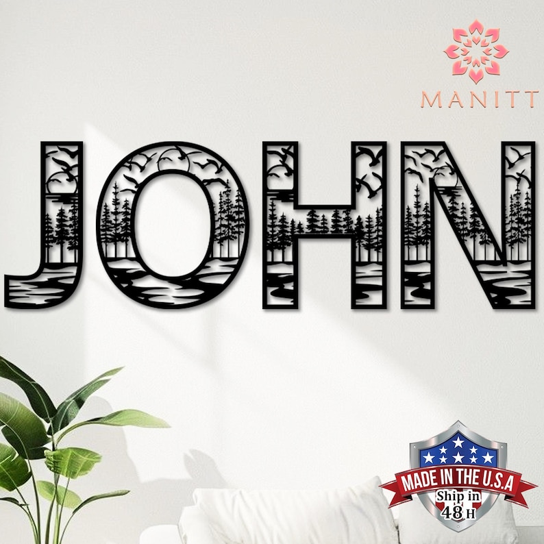 Pode incluir: Arte de parede em metal preto que soletra "JOHN", apresentando uma cena da natureza dentro de cada letra. O design inclui &aacute;rvores, &aacute;gua e p&aacute;ssaros voando. A marca "MANITT" &eacute; vis&iacute;vel, juntamente com um emblema "Made in the U.S.A.".