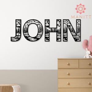 Pode incluir: Arte de parede em metal preto com a palavra "JOHN", com uma cena da natureza dentro de cada letra. O design inclui &aacute;rvores, &aacute;gua e p&aacute;ssaros voando, criando uma pe&ccedil;a decorativa e personalizada.
