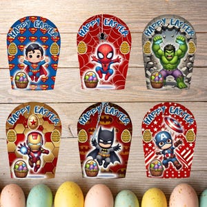 May include: Six Easter-themed gift bags featuring superheroes Superman, Spider-Man, Hulk, Iron Man, Batman, and Captain America. Each bag has a "Happy Easter" banner, Easter eggs, and a basket of colorful eggs. The bags are on a wooden surface.