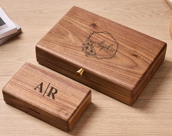 May include: Two wooden boxes with a natural wood grain finish. The larger box has a floral design with the name "Sophie" inside a geometric frame. The smaller box has the initials "A/R". Both boxes have a brass-colored knob.
