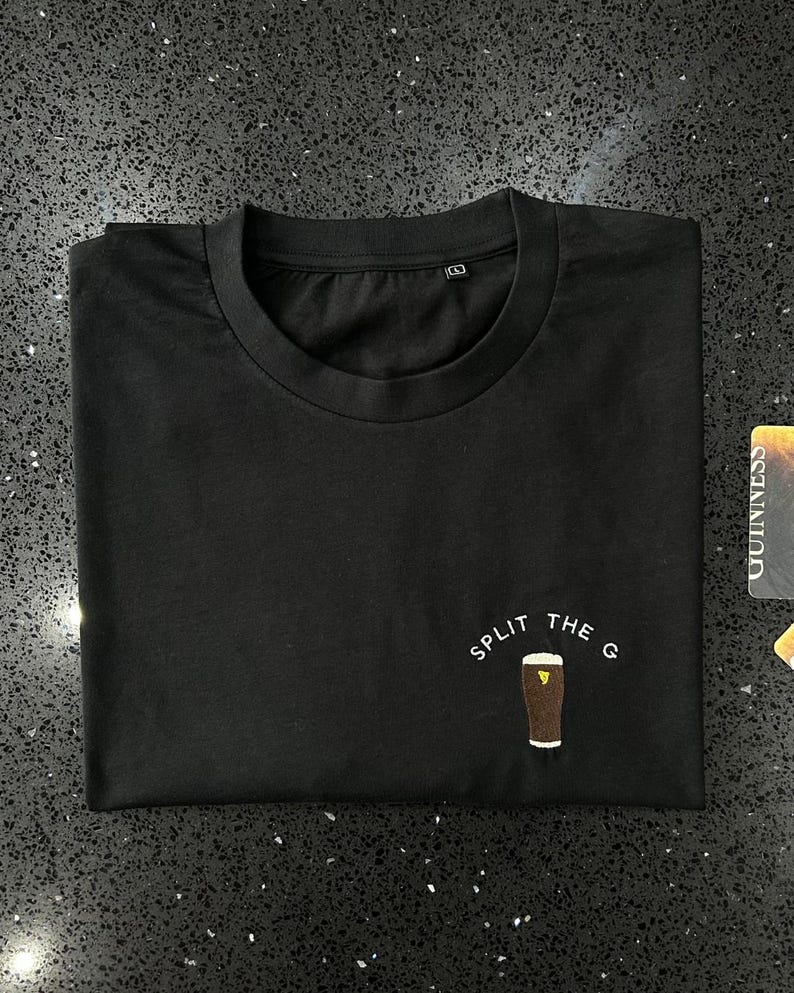 May include: Black t-shirt with white text that reads "Split the G" and a graphic of a pint of Guinness.