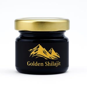 May include: A small, black glass jar with a gold lid. The jar has a black label with a gold mountain graphic and the words "Golden Shilajit" in gold lettering. The jar is filled with a dark substance.