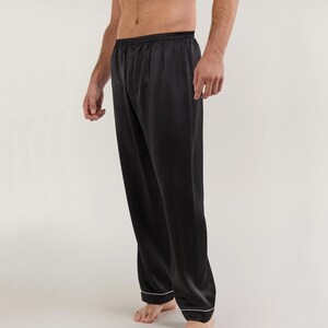 May include: Black satin pajama pants with a white trim around the waistband and legs.