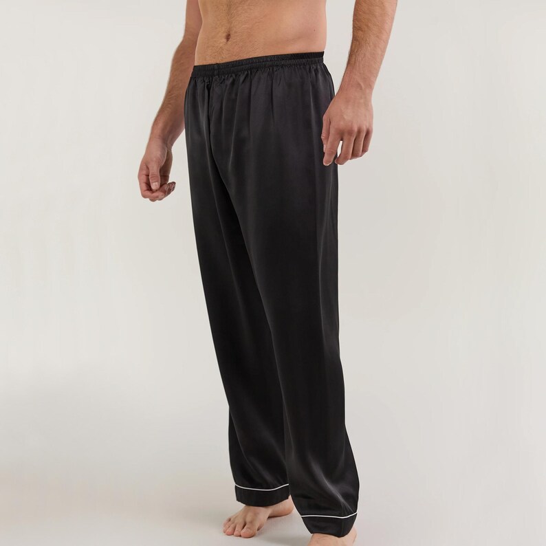 May include: Black satin pajama pants with a white trim around the waistband and legs.