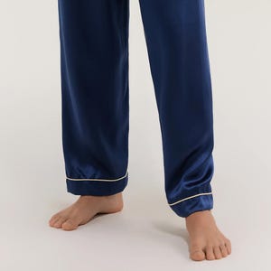 May include: Navy blue satin pajama pants with a thin white trim around the bottom hem.