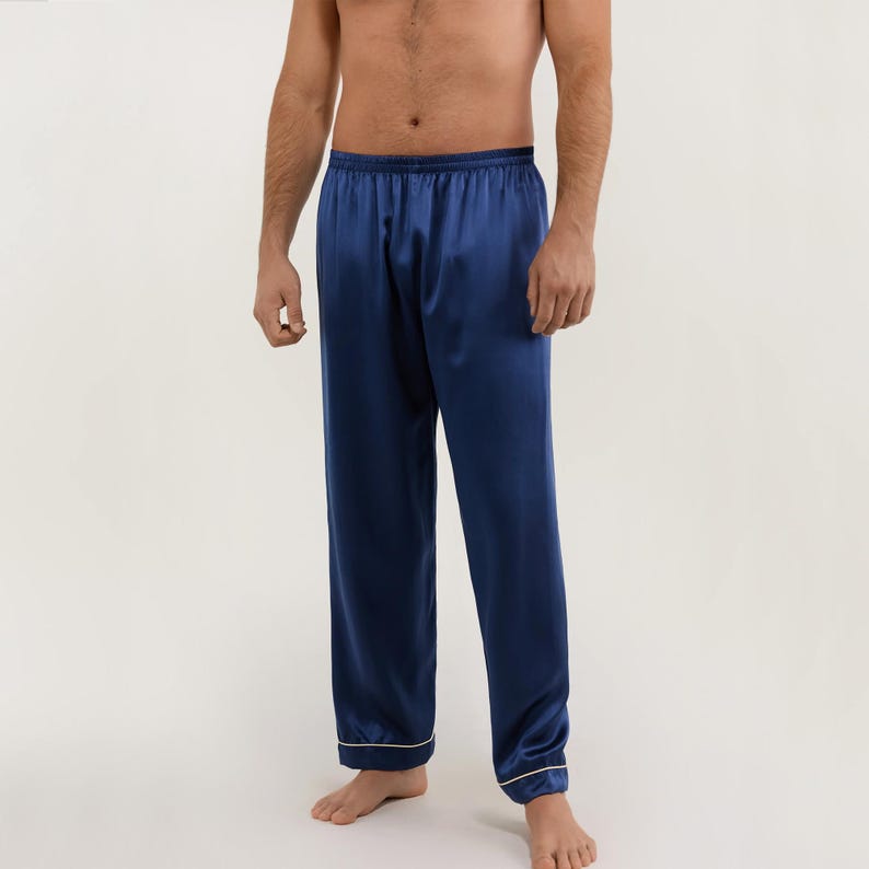 May include: Navy blue satin pajama pants with a white trim. The pants have an elastic waistband and a relaxed fit.