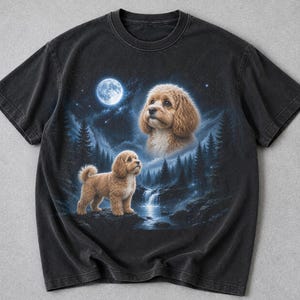 May include: Black t-shirt featuring a detailed illustration of a dog in a forest setting under a full moon. The design includes a waterfall, trees, and a second dog portrait. The artwork is rendered in shades of brown, blue, and white.