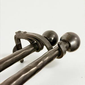 Puede incluir: Dos barras de cortina de metal marrón oscuro con terminales de bola. Las barras tienen un aspecto texturizado, ligeramente martillado. Los soportes también son de color marrón oscuro y tienen un diseño simple y funcional. Las barras están diseñadas para montarse en una pared.