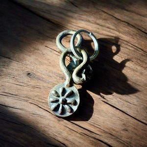 May include: A silver metal key chain with a decorative flower design. The key chain has a loop for attaching keys.