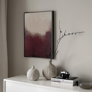 May include: A white ceramic vase with a textured surface, a smaller white ceramic vase with a textured surface, and a black camera on a white table with a stack of books. The books have black and white covers with text on them. A branch with black berries is in the vase.