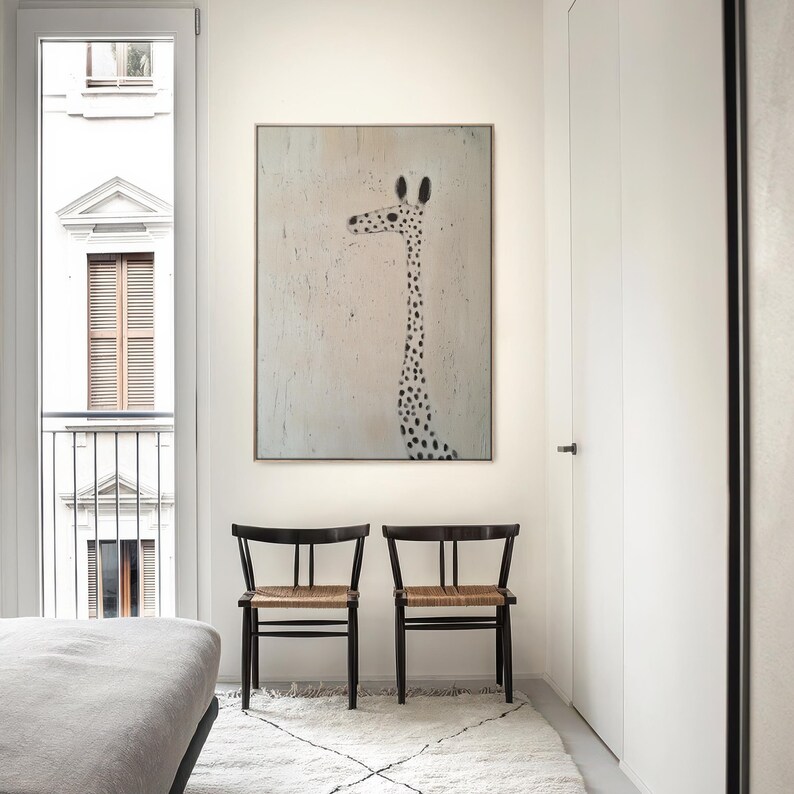 May include: A white room with a large framed painting of a giraffe with black spots on a light pink background. Two black chairs with woven seats are in front of the painting. A white rug is on the floor.