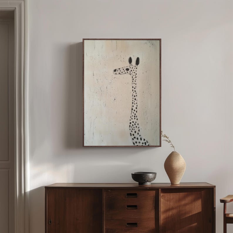 May include: A framed painting of a black and white spotted giraffe with a long neck on a light pink background.