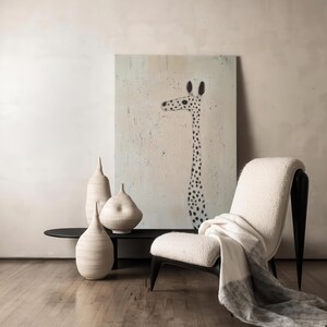 May include: A white chair with a black frame and a white throw blanket sits in front of a painting of a giraffe with black spots on a light pink background. Three white ceramic vases are on a black table in front of the chair.