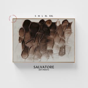 Puede incluir: Impresión de arte abstracto con un diseño marrón y blanco con formas orgánicas. La impresión está enmarcada en un fino marco dorado. El texto "SALVATORE ART PRINTS" está impreso debajo de la imagen.