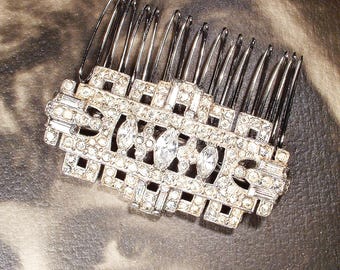 May include: A silver hair comb with a geometric design, encrusted with clear rhinestones.