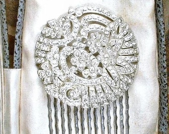 May include: A circular silver-tone hair comb featuring an intricate floral and scrollwork design. The entire surface is encrusted with numerous small, clear, sparkling rhinestones arranged in a dense, decorative pattern across the metal base.