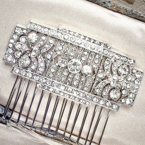 May include: A silver hair comb with a decorative design of rhinestones and a geometric pattern.