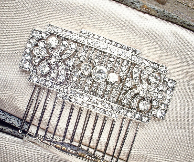 May include: A silver hair comb with a decorative design of rhinestones and a geometric pattern.