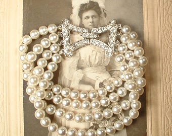 Peut inclure: Un bracelet multi-rangs composé de quatre rangées de perles blanches rondes reliées par un fermoir en métal argenté. Le fermoir a la forme d'un nœud et est incrusté de strass transparents et étincelants qui captent la lumière avec éclat.