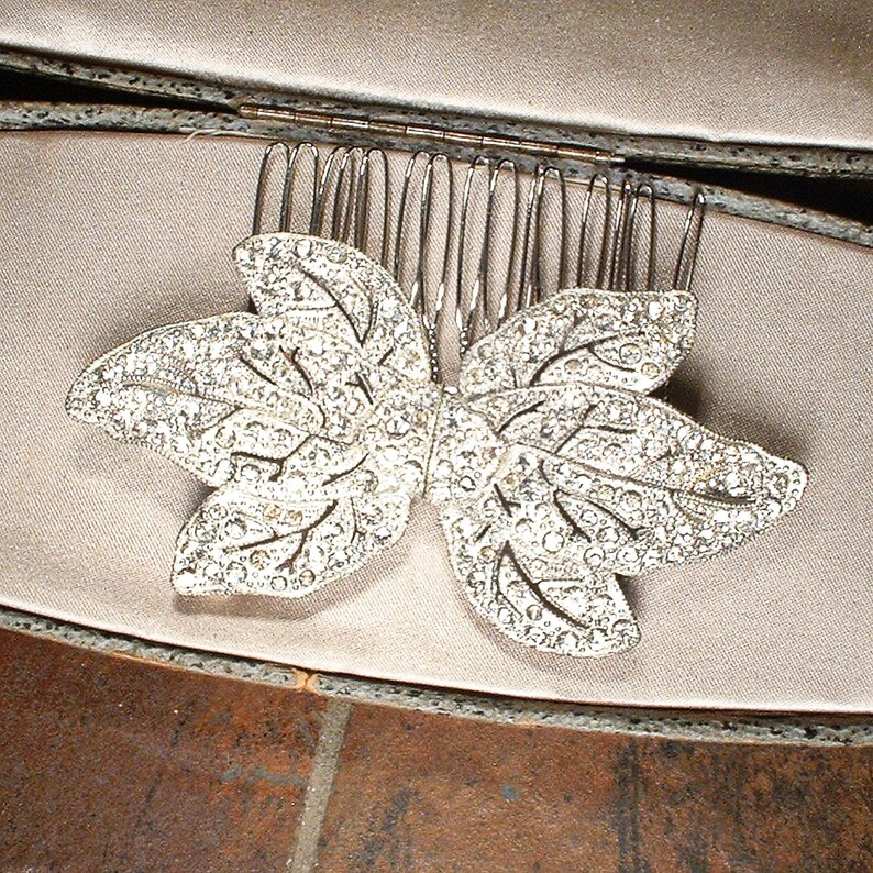 Peut inclure: Un peigne &agrave; cheveux argent&eacute; orn&eacute; d'un motif de feuille incrust&eacute; de strass &eacute;tincelants. Le peigne est dot&eacute; de fines dents argent&eacute;es. Cet accessoire est id&eacute;al pour les occasions sp&eacute;ciales. Les strass sont clairs.