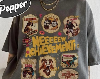 May include: Dark gray t-shirt with multiple cartoon graphics and text. The shirt features various images of cats, a goat, and a dinosaur, along with the words "NEEEEEW ACHIEVEMENT!" and "COMFORT COLORS Pepper".