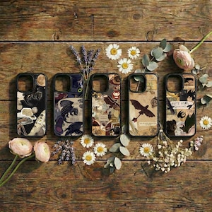 May include: Five phone cases with unique designs featuring dragons and other fantasy elements. The cases are black with various illustrations and collage-style backgrounds. The cases are arranged on a rustic wooden surface with flowers.