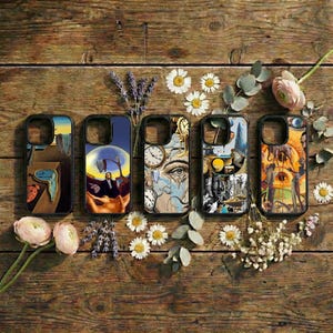 May include: Five phone cases with surrealist art designs are displayed on a wooden surface. The cases feature images of melting clocks, faces with clocks, and other abstract artwork. The cases are black with colorful artwork.
