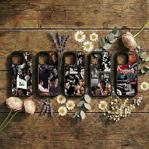 May include: Five black phone cases with collages of images from the movie "The Godfather" are displayed on a wooden surface. The cases feature various scenes and characters from the film. The arrangement includes flowers and greenery.