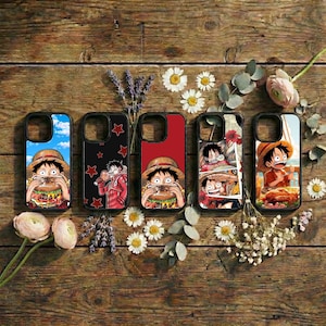Könnte beinhalten: Fünf Handyhüllen mit farbenfrohen Grafiken im Anime-Stil, die eine Figur beim Essen eines Burgers und andere Szenen zeigen. Die Hüllen sind schwarz mit verschiedenen Hintergrundfarben, darunter Blau, Rot und ein Collage-Design. Sie liegen auf einer Holzoberfläche mit Blumen.