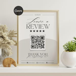 May include: A framed print with a gold border, displaying the text "Leave a REVIEW" above a QR code. The words "THANK YOU for supporting us!" are below the QR code. Social media handles are at the bottom.