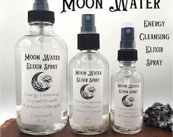 May include: Three glass bottles with spray tops filled with clear liquid. The bottles are labelled "Moon Water Elixir Spray" and have different crystal accents. The labels also list the scent of each bottle: Unscented, Lilac, and Rose. The bottles are arranged from largest to smallest. The text "Moon Water Energy Cleansing Elixir Spray" is written in large letters at the top of the image.