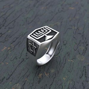 Puede incluir: Un anillo de plata con un esmalte negro que representa una menorá y una estrella de David.