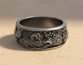 Può includere: Un ampio anello in metallo color argento caratterizzato da un dettagliato intaglio in rilievo di un drago mitico con squame, pinne fluenti e tratti del volto complessi che avvolgono l'intera circonferenza esterna della fascia.