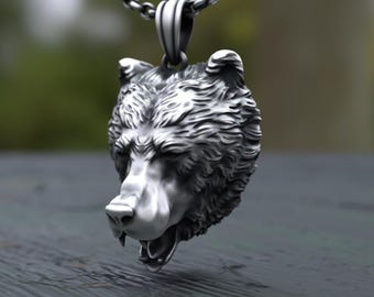 May include: A silver-toned metal pendant shaped like a detailed bear head with a textured fur finish and an open mouth, suspended from a matching silver-toned metal chain link necklace. The design features deep shadows and highlights on the bear's face.
