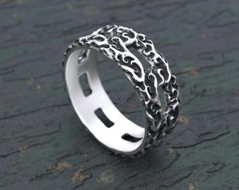 Puede incluir: Un anillo de tono plateado que presenta un patrón orgánico, intrincado, elevado y texturizado en la banda exterior. El diseño incluye recortes rectangulares abiertos a los lados, creando una apariencia hueca y estratificada con una superficie interior pulida.