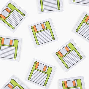 May include: A set of ten green and orange floppy disk shaped sticky notes. The notes are on a white background.