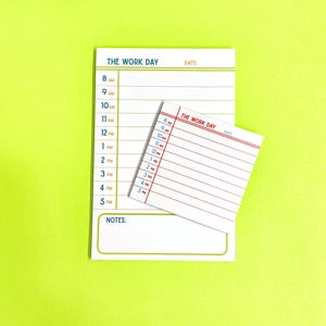 May include: Two white notepads with the text "THE WORK DAY" and a schedule from 8 AM to 5 PM. The larger notepad has a gold border and the smaller one has a red border. The background is bright green.