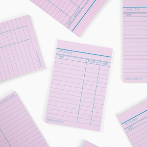 May include: A collection of pink to-do list notepads with blue grid lines and text. Each notepad features sections for tasks, due dates, and completion status. The text "TO-DO LIST" and "MARIGOLDPRESS.CO" are visible.